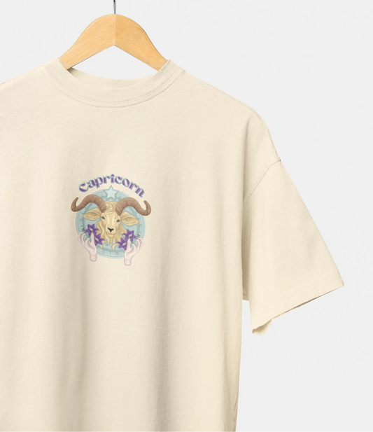 Beige t-shirt with Capricorn zodiac design on a hanger against a white background