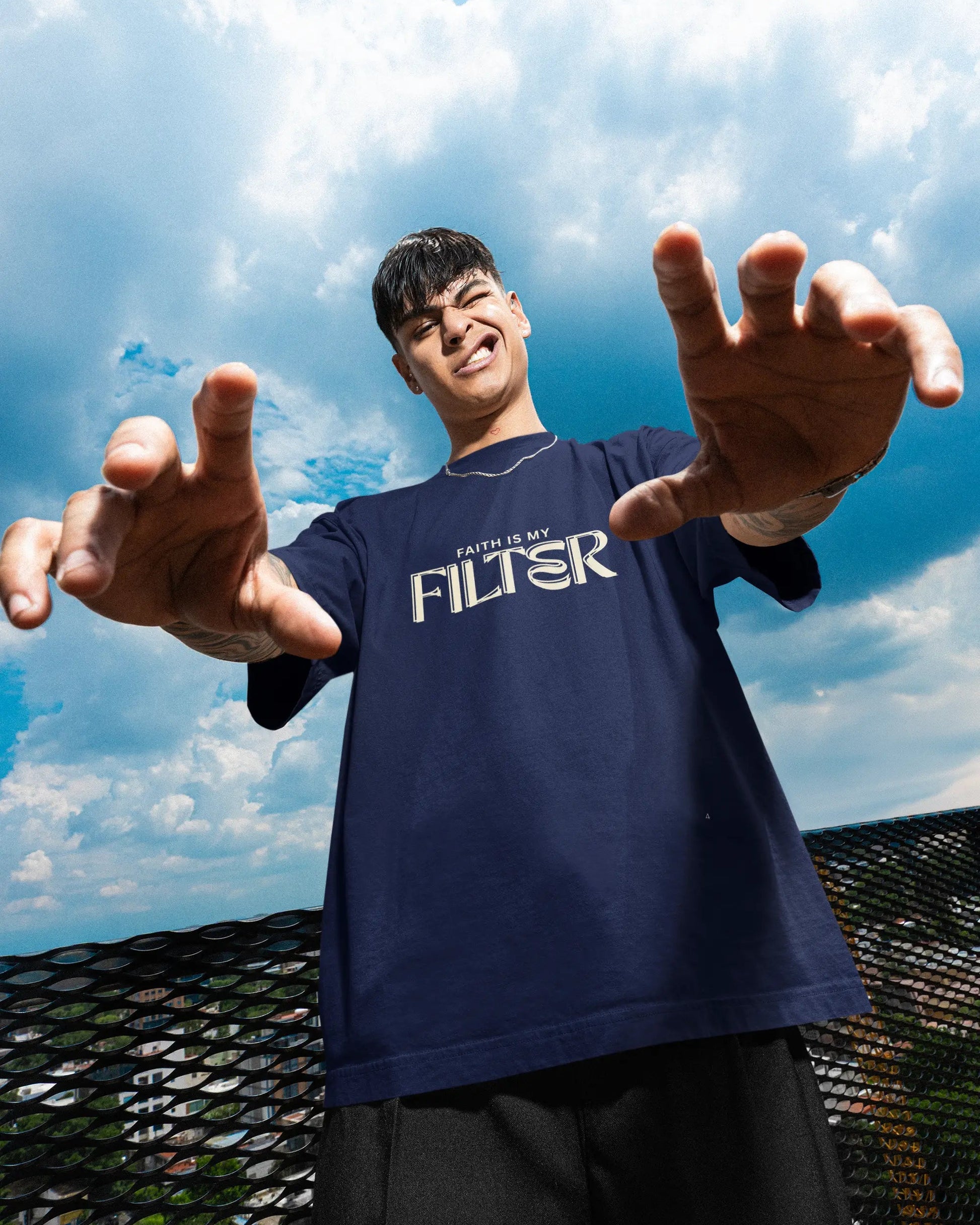 Person wearing a black t-shirt with text, standing outdoors against a blue sky.