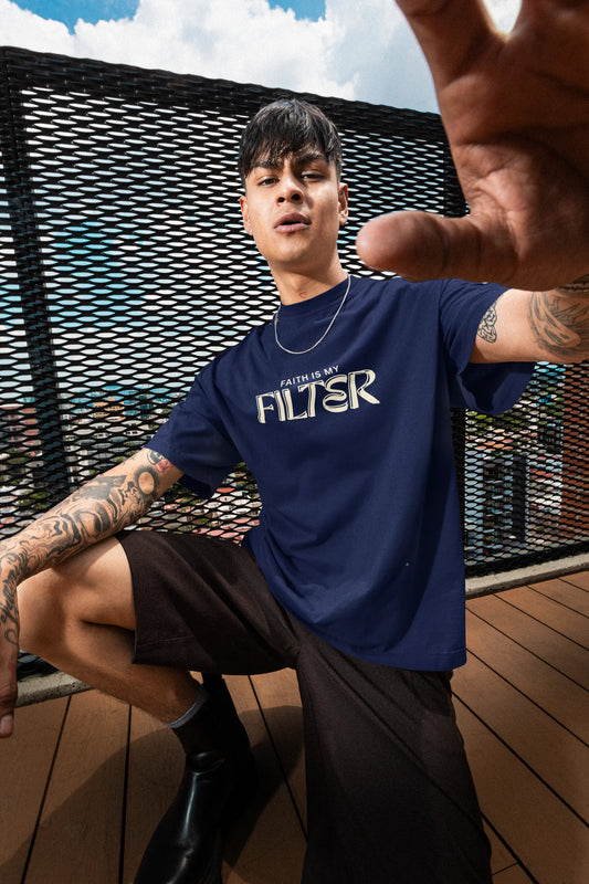 A tattooed man wearing a navy blue faith is my filter t-shirt.