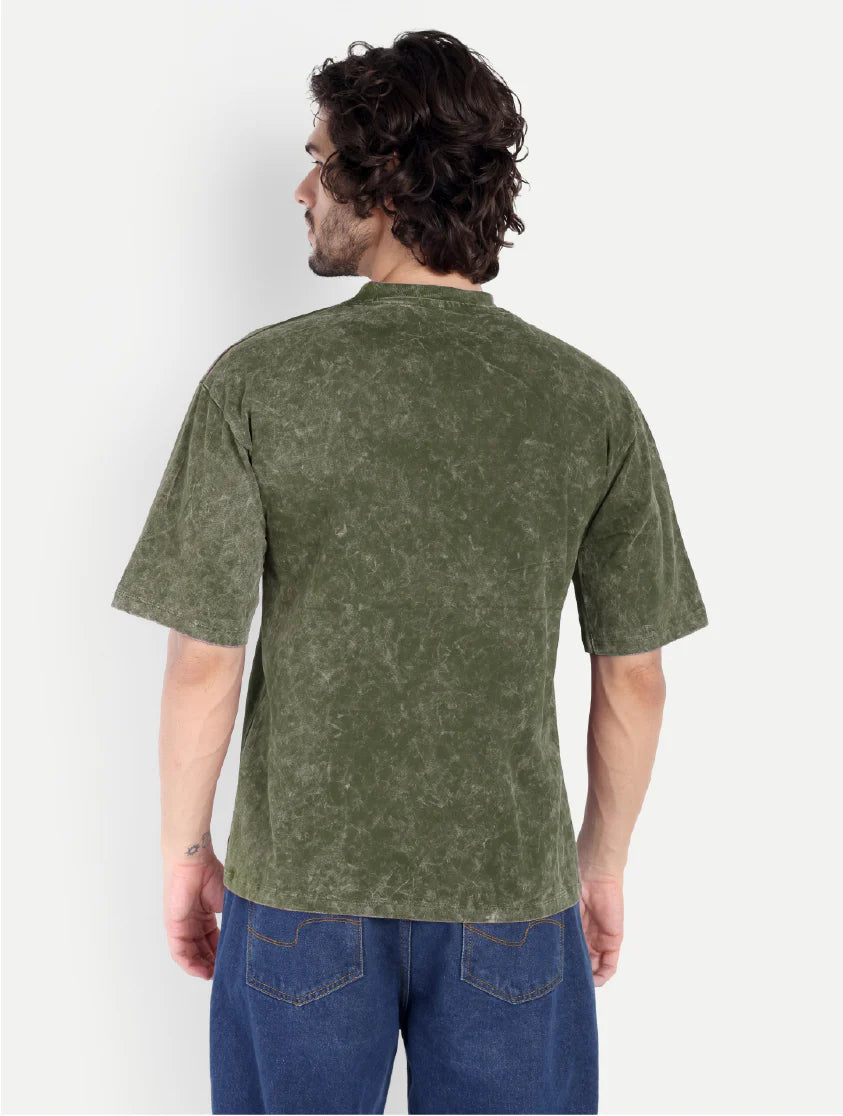 Man wearing a green t-shirt and blue jeans against a white background