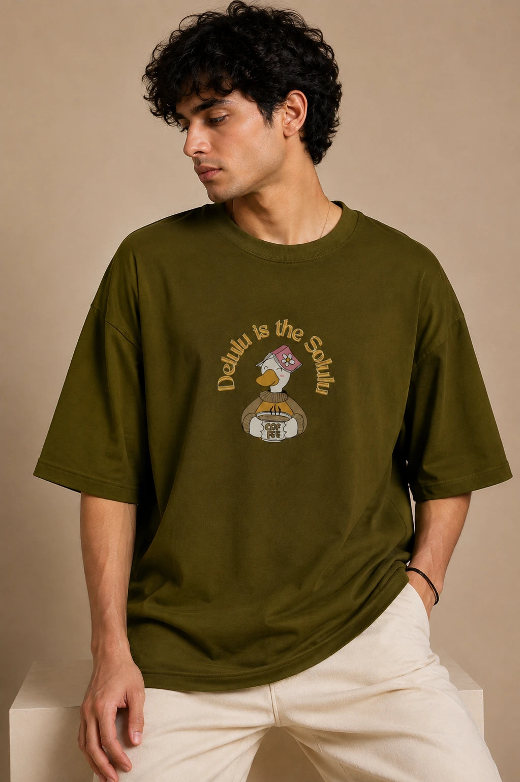 Male model wearing Delulu Is The Solulu olive green unisex graphic streetwear T-shirt made from premium 240 GSM cotton